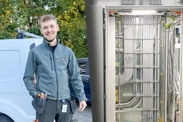 Elektriker Simon Gabrielsson till vänster. Till höger syns apparatskåpet som hans pappa delade på Linkedin och fick mycket beröm för. Det är ett elskåp i industriell miljö med prydligt dragna och märkta kablar.